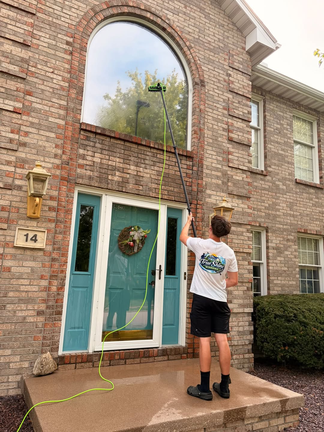 True Shine technician cleaning a tall arched window